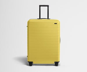 Front product view of The Large suitcase in Sunshine Yellow with raised handle
