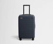 Dark blue suitcase with a visible college logo on a light gray background