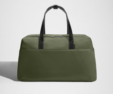 Green duffel bag with black straps on a light gray background