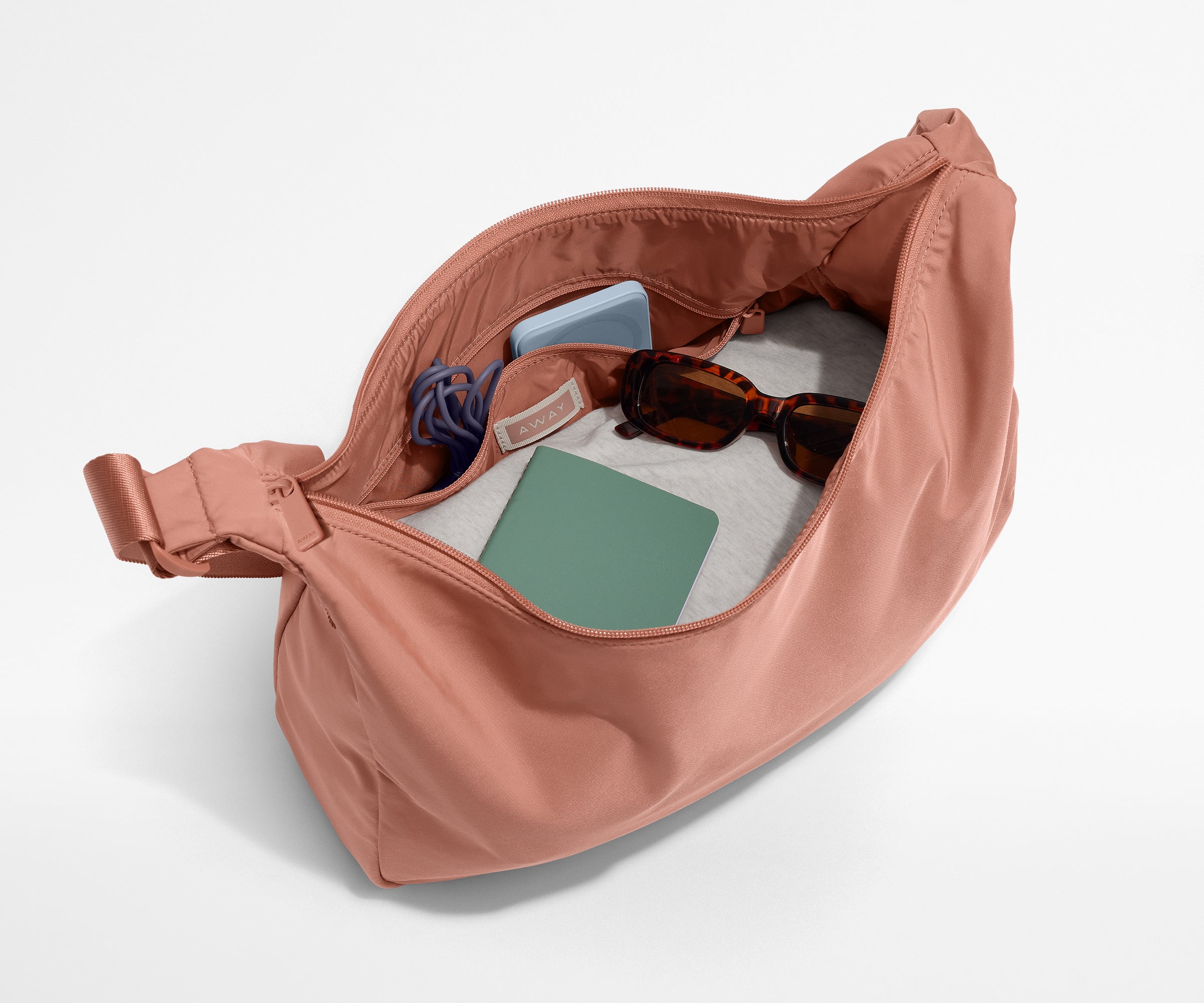 Featherlight crossbody packed with a sweater, notebook, sunglasses, and portable charger