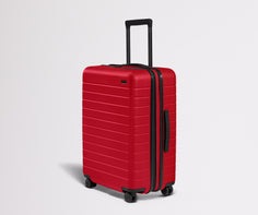 Red suitcase with black handle and wheels on a light gray background