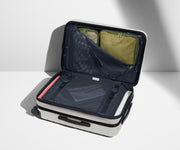 The Bigger Carry-On Flex suitcase in Cloud Gray shown open on its side and packed with Away's packing organizers to show capacity and the interior compression system, designed to help you pack more in