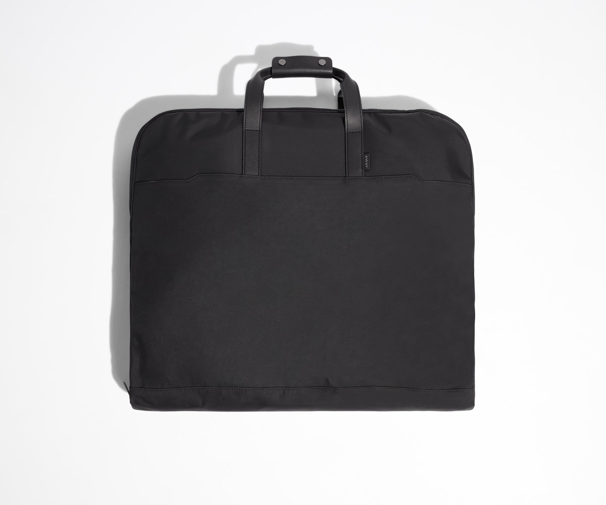 Black garment bag folded view with leather trim handles.