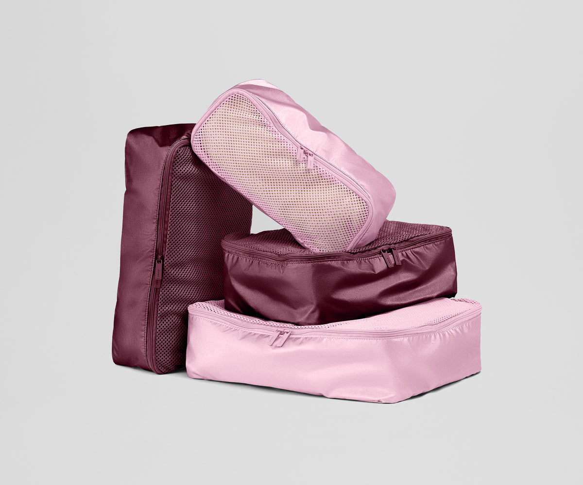 Set of pink and maroon packing cubes on a light gray background