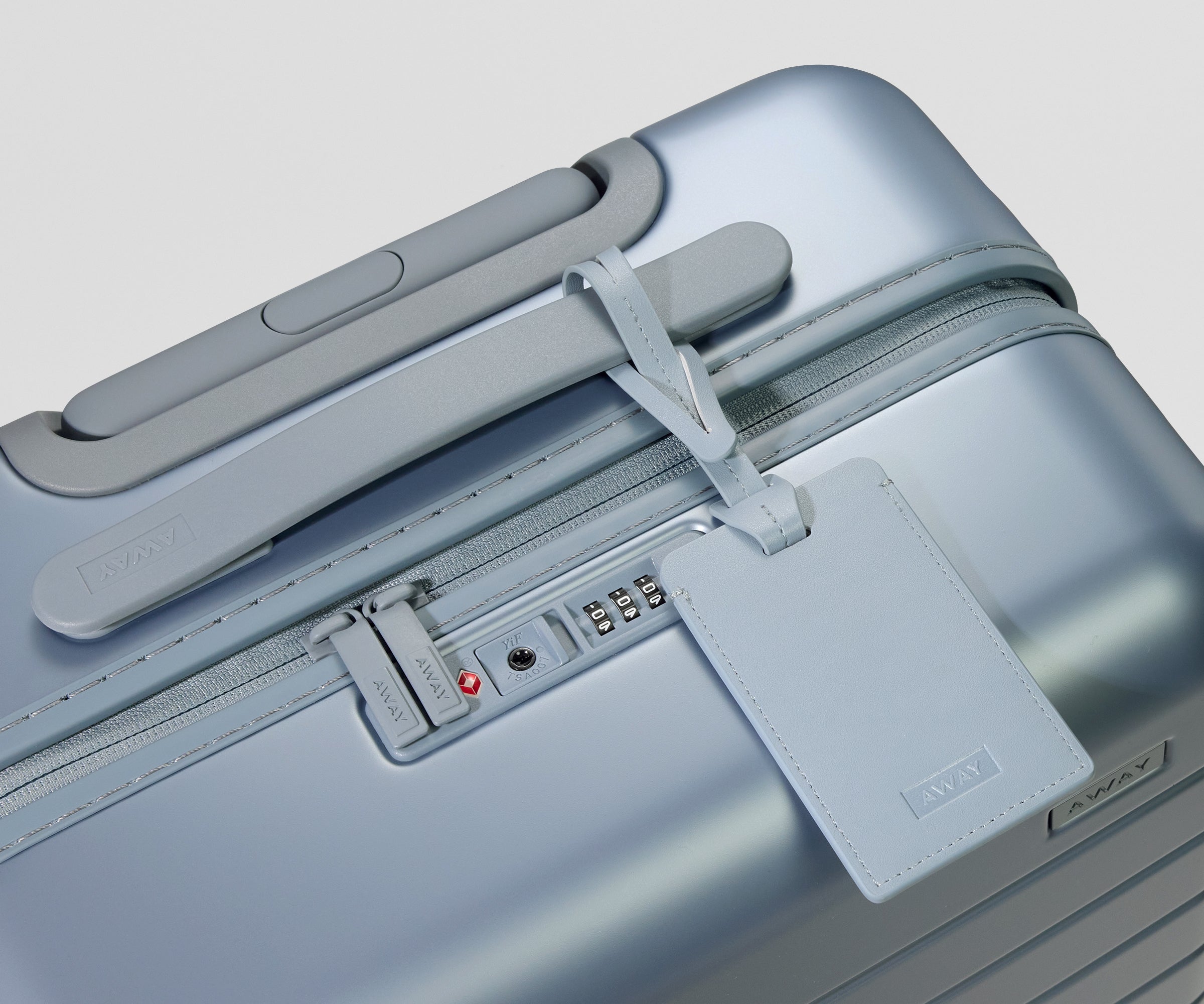 Light blue suitcase with a luggage tag on a light gray background