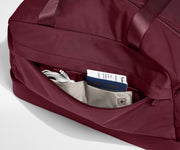 Maroon tote with a pocket open, revealing travel documents and cables.