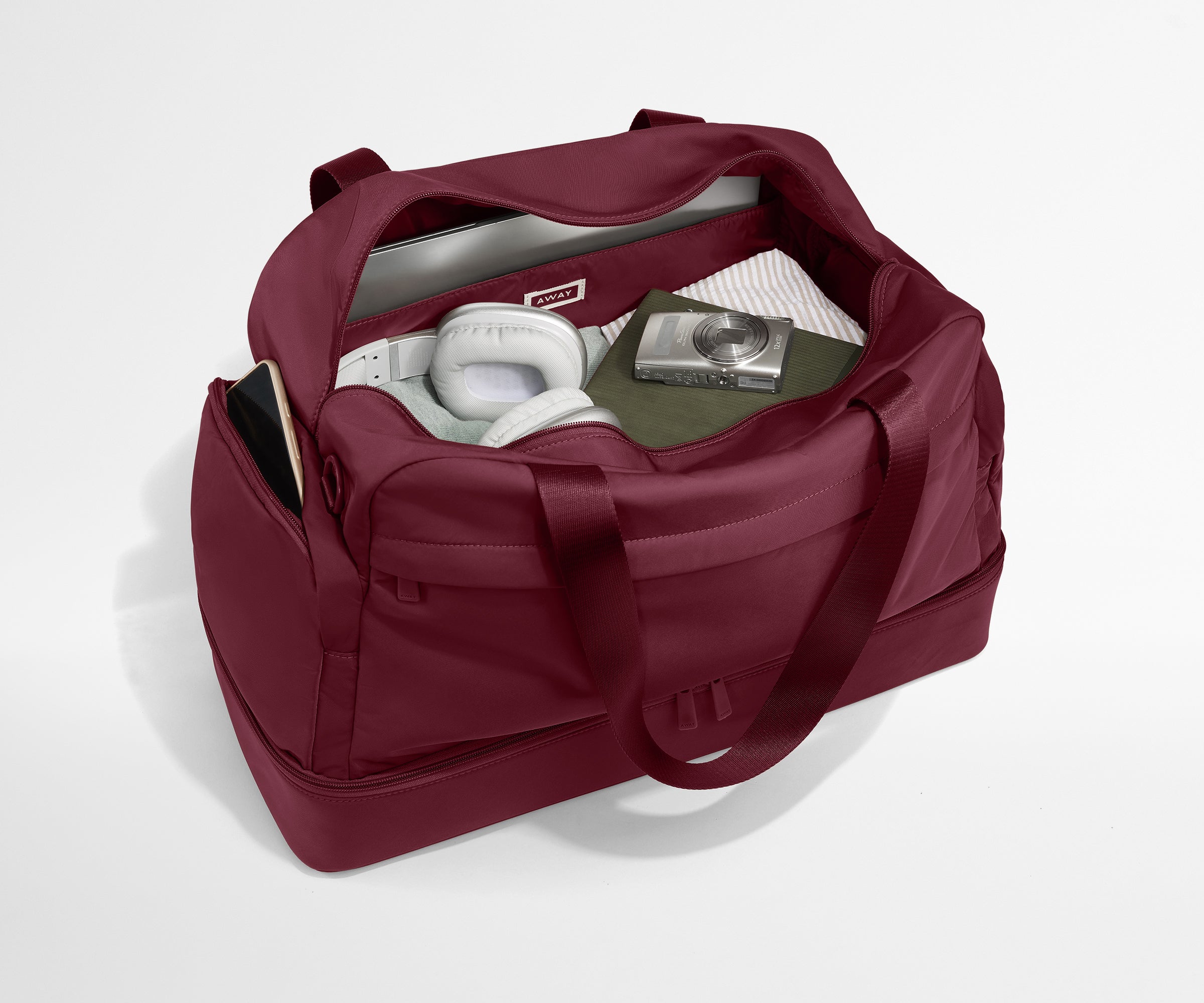 Maroon duffel bag with items inside on a white background