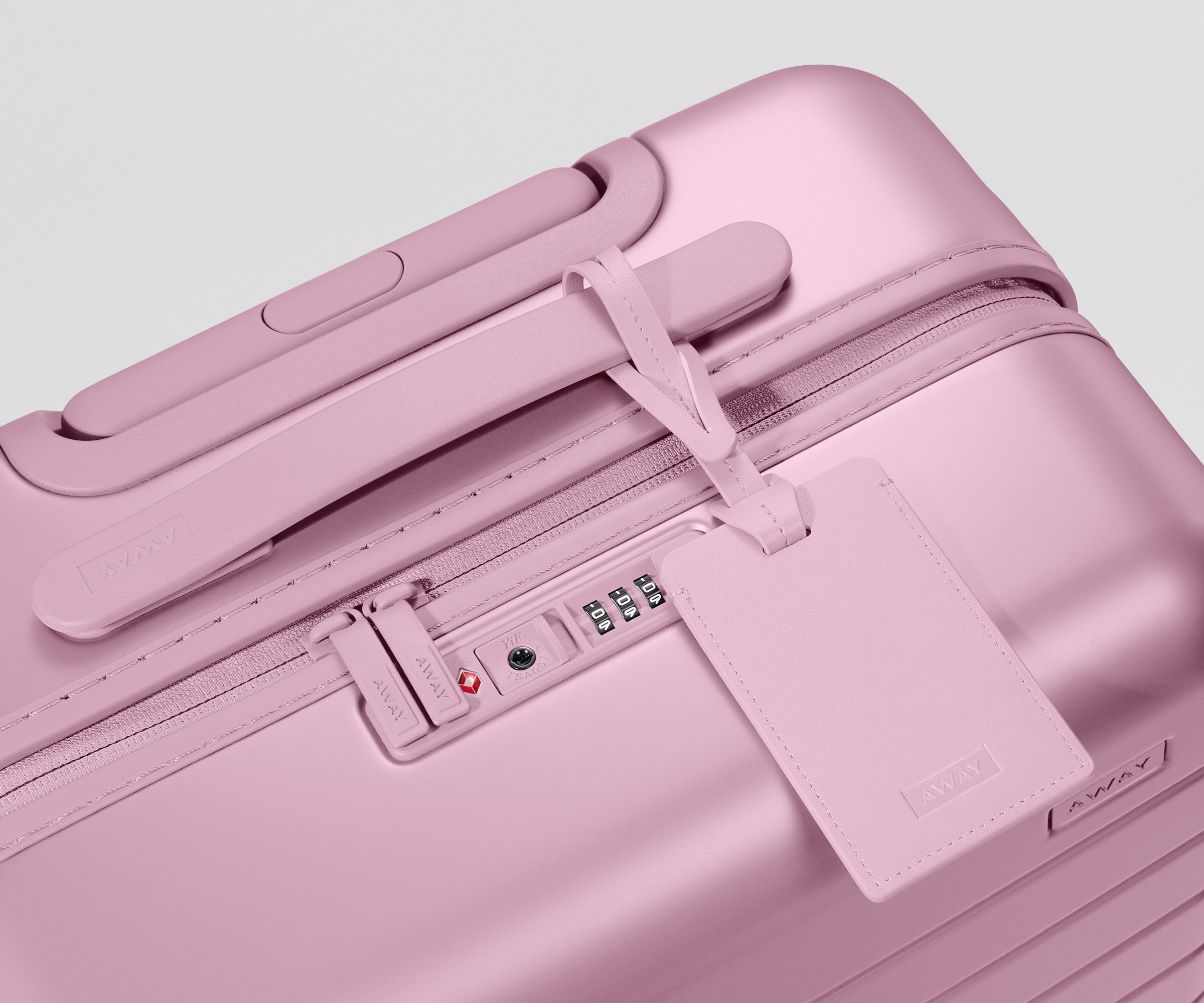 Pink suitcase with a luggage tag on a light gray background