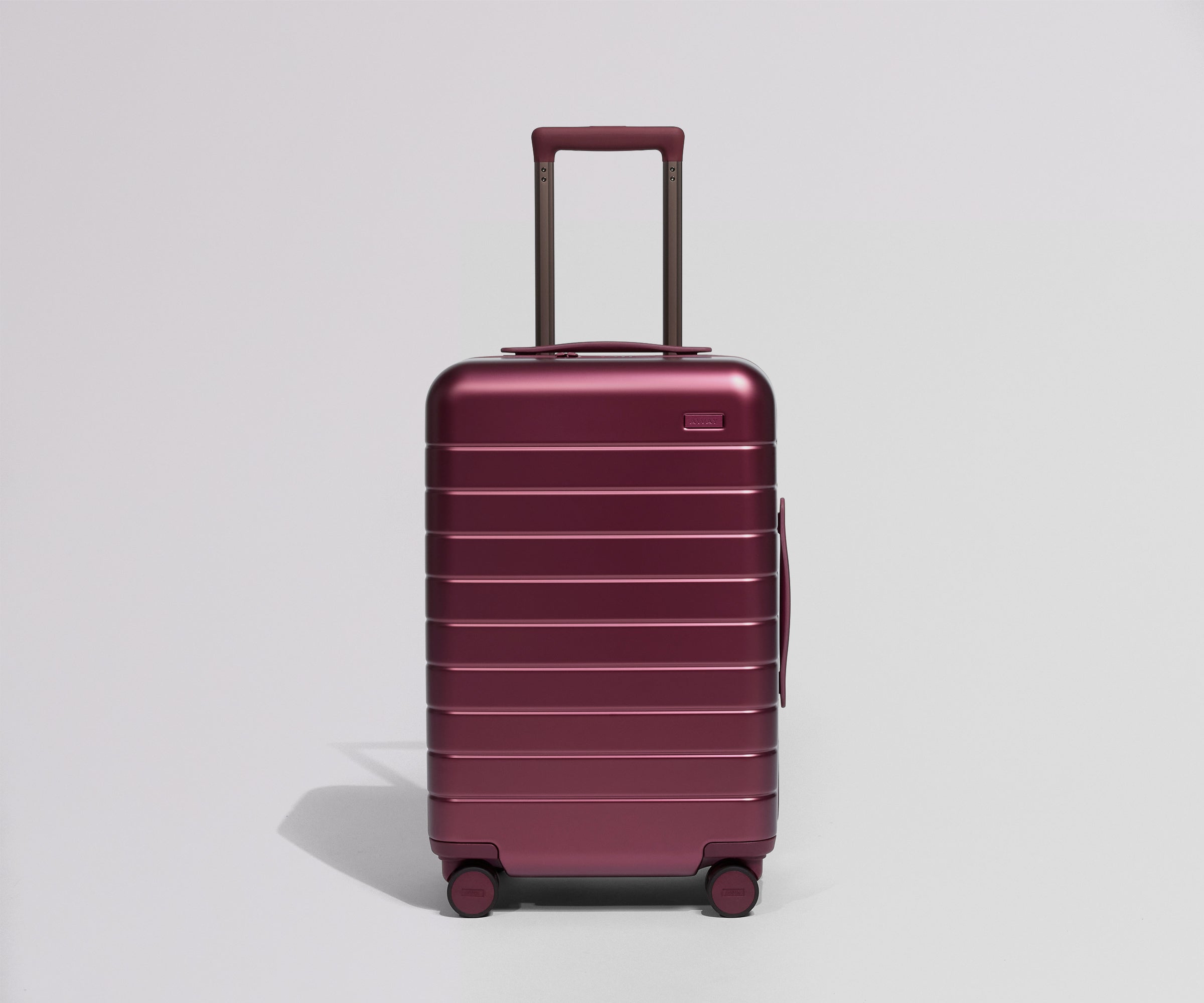 Maroon suitcase with a visible brand logo on a light gray background