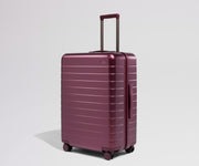 Maroon suitcase with a handle on a light gray background
