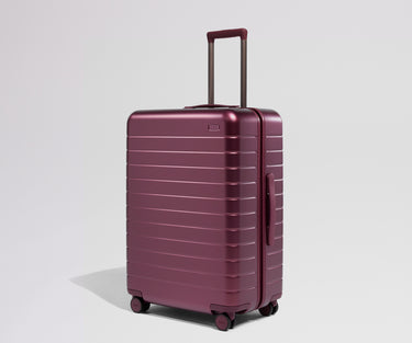 Maroon suitcase with a handle on a light gray background