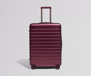 Maroon suitcase with a handle on a light gray background