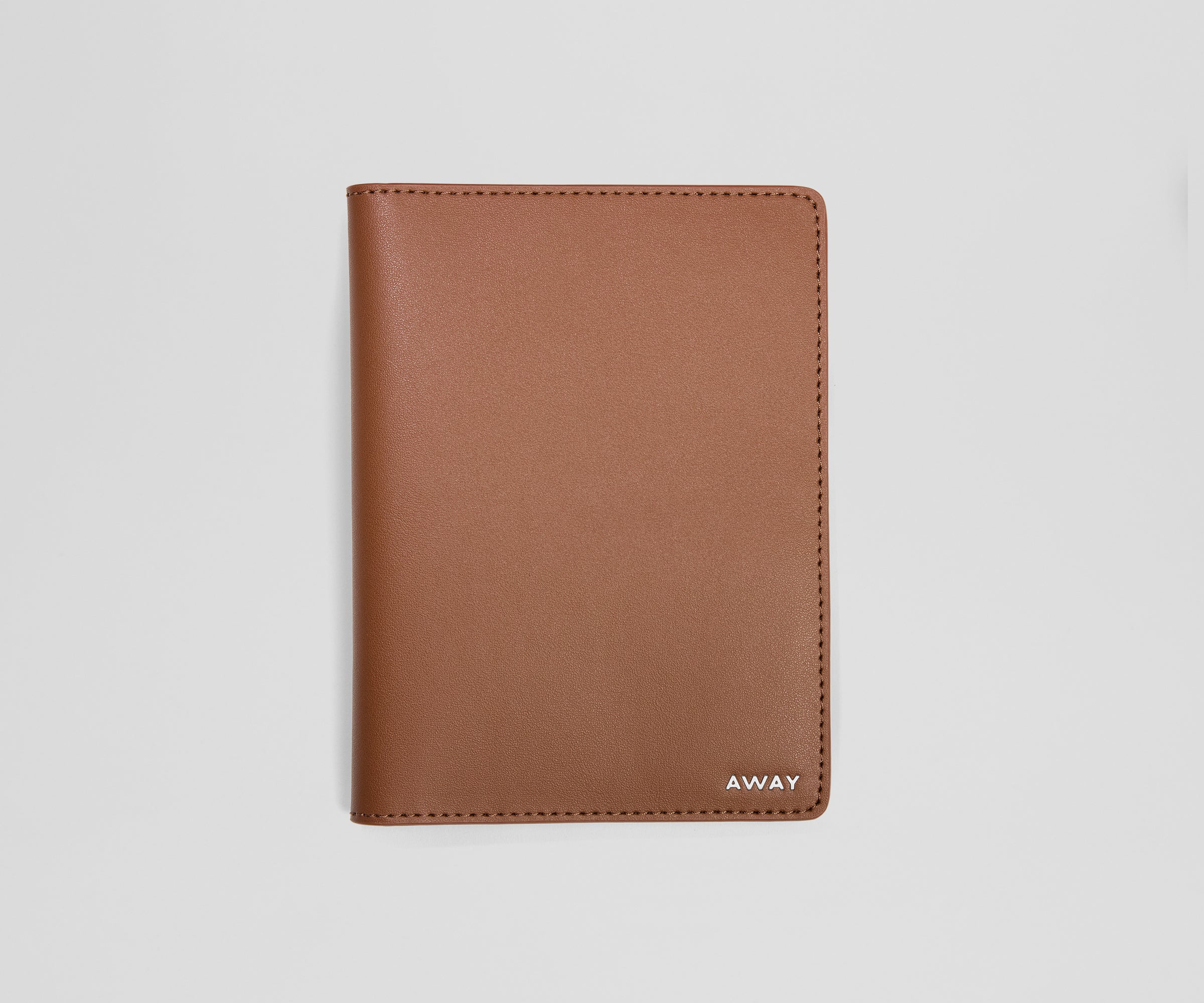 Brown leather passport holder with 'AWAY' branding on a light gray background