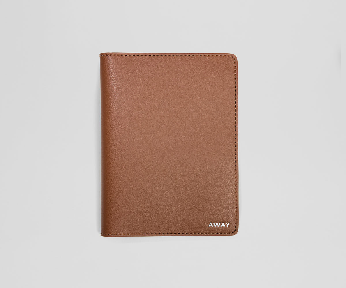 Brown leather passport holder with 'AWAY' branding on a light gray background