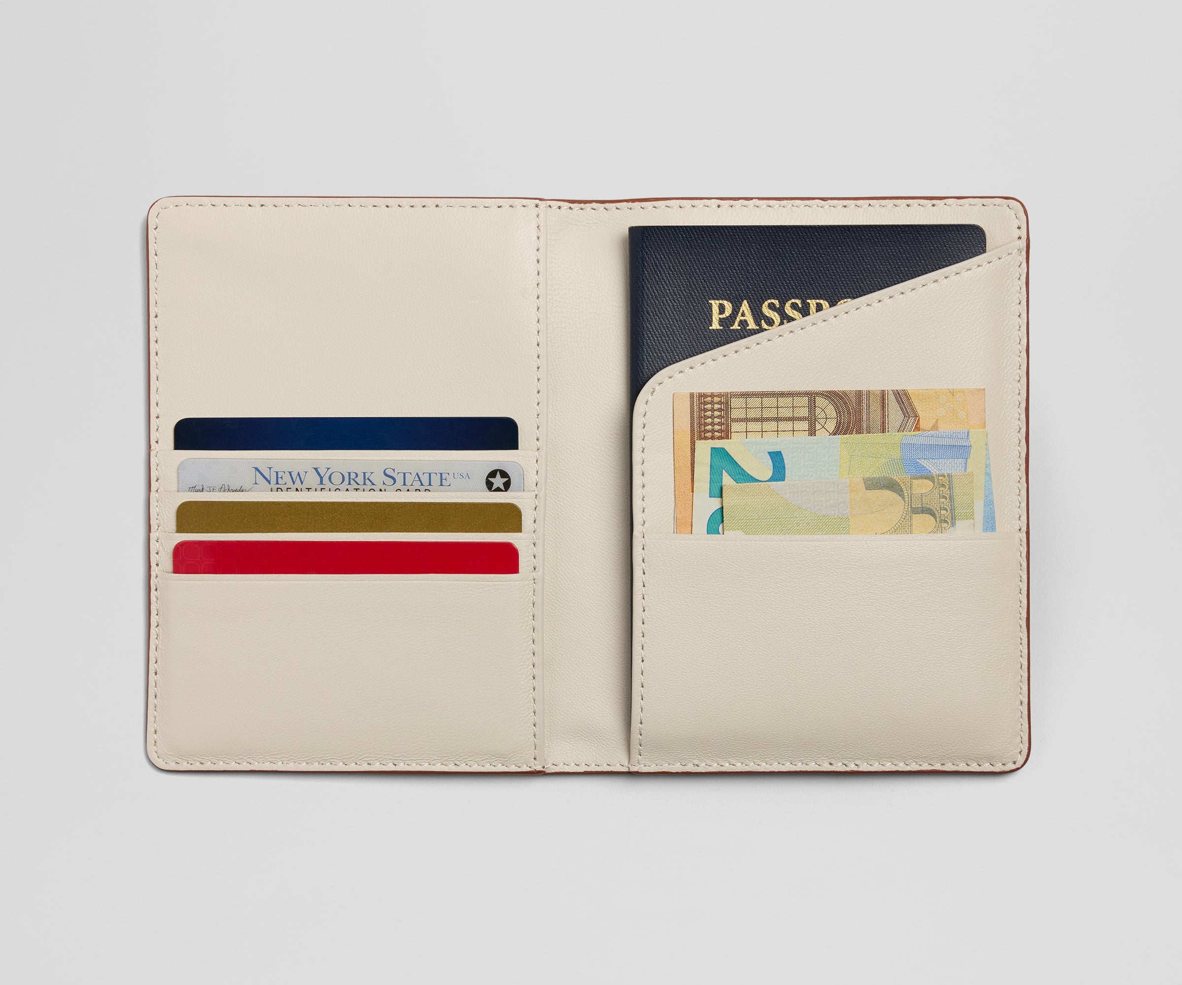 Passport holder with compartments for a passport, cards, and money on a light gray background