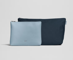 Two pouches, one light blue and one navy, on a light gray background
