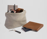 Beige pouch with items and a brown pouch on a light gray background