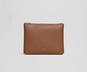Brown leather pouch with 'AWAY' branding on a light gray background
