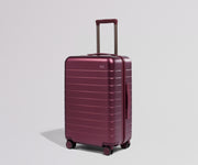 Maroon suitcase on a light gray background
