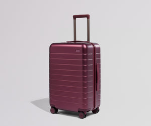 Maroon suitcase on a light gray background