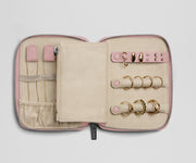 Pink jewelry case with gold rings on a light gray background