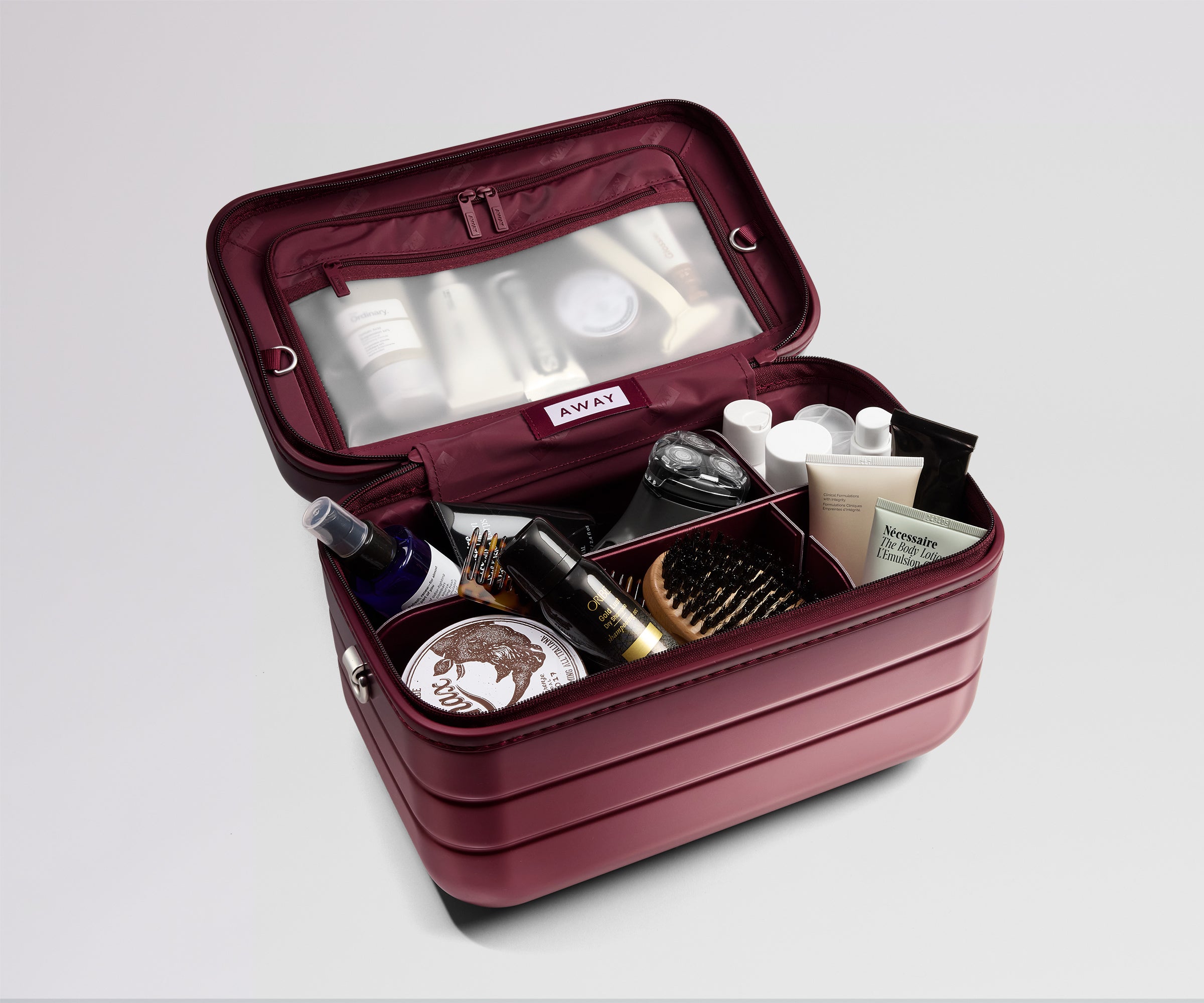 Open red cosmetic case with various items on a light gray background
