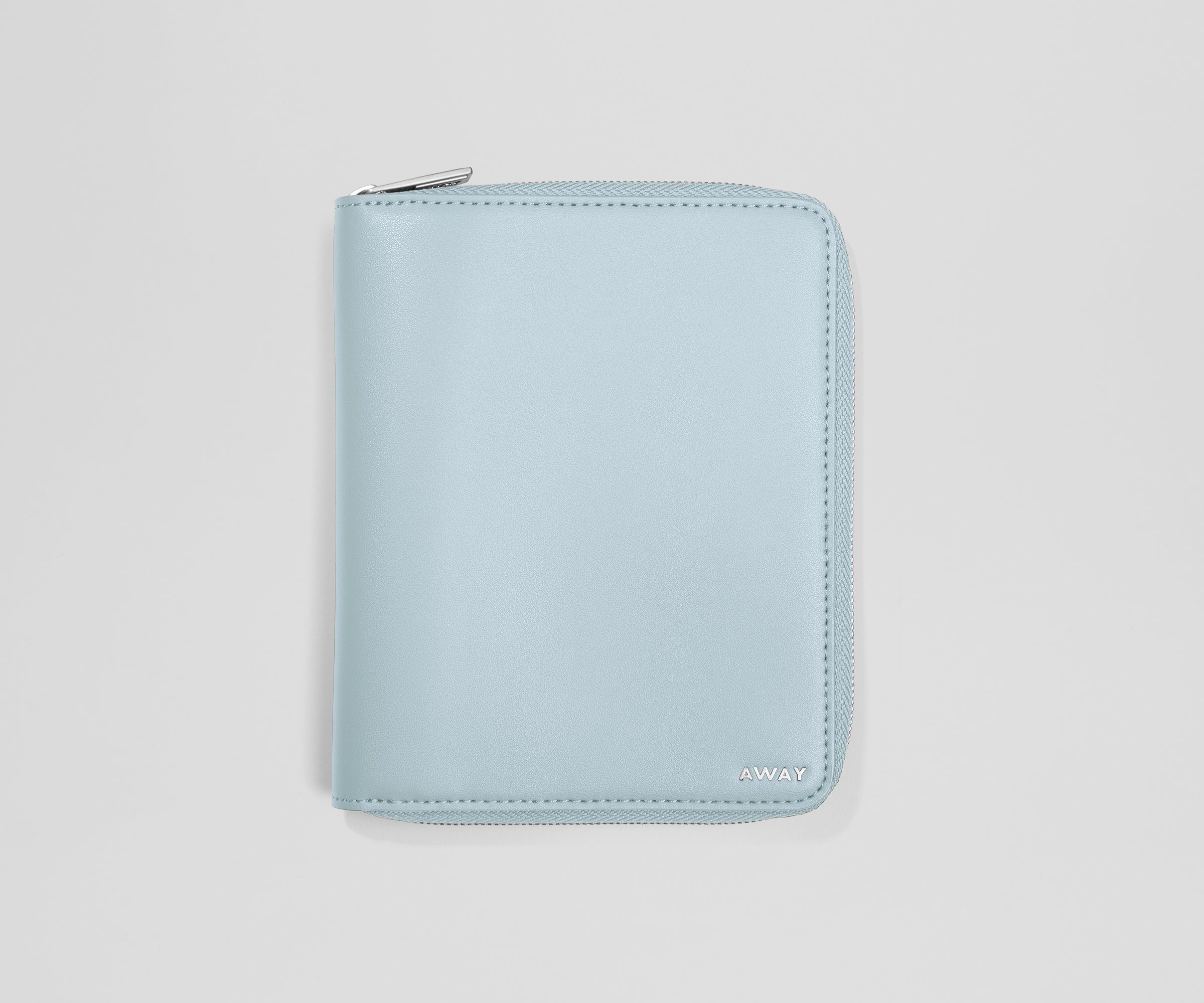 Light blue travel wallet with an AWAY logo on a light gray background