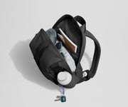 Daypack packed with a light jacket, sunglasses, notebook, map, and other travel gear. Water bottle featured in the exterior water bottle pocket.