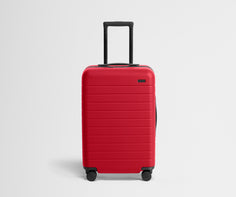 Red suitcase with black wheels on a light gray background