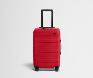 Red suitcase with a black handle on a light gray background