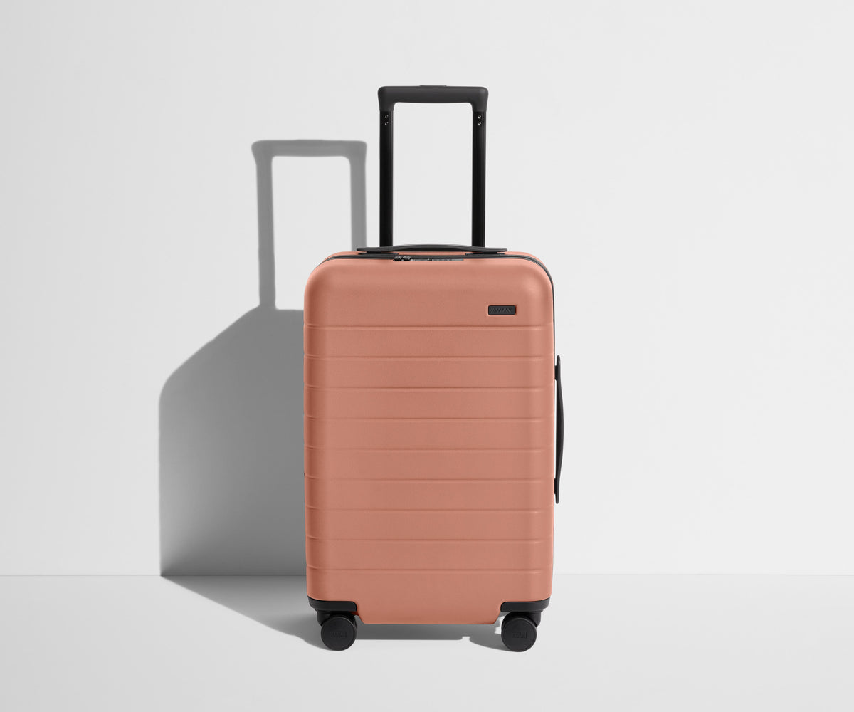 Front product view of The Carry-On suitcase in Clay Pink with raised handle