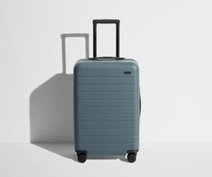 Front product view of The Bigger Carry-On suitcase in Coast Blue with raised handle