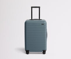 Front product view of The Bigger Carry-On suitcase in Coast Blue with raised handle