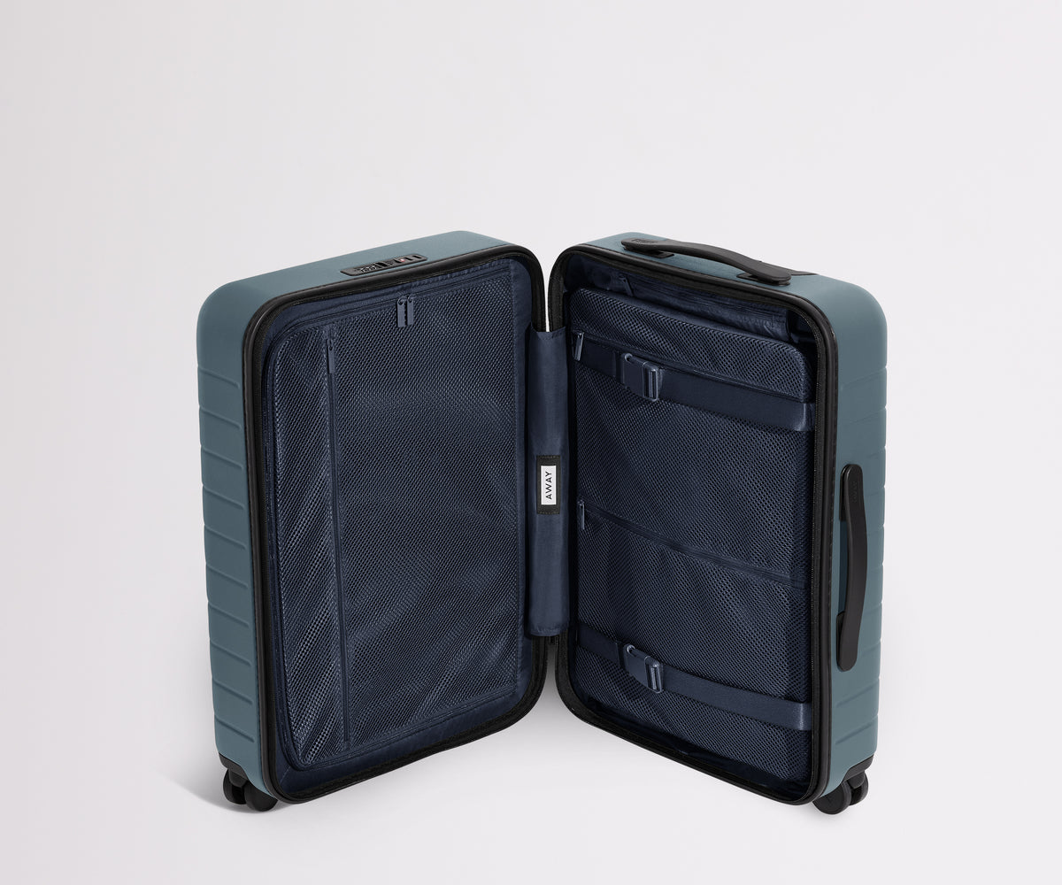 The Bigger Carry-On suitcase in Coast Blue shown open in an upright position to show interior organization and compression system