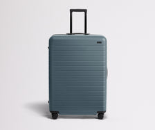 Front product view of The Large suitcase in Coast Blue with raised handle