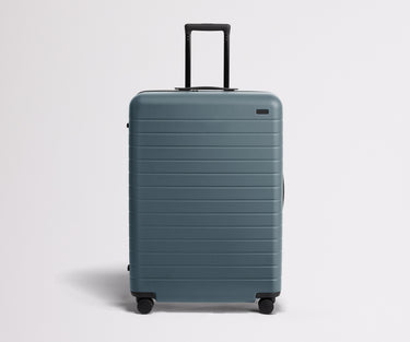 Front product view of The Large suitcase in Coast Blue with raised handle