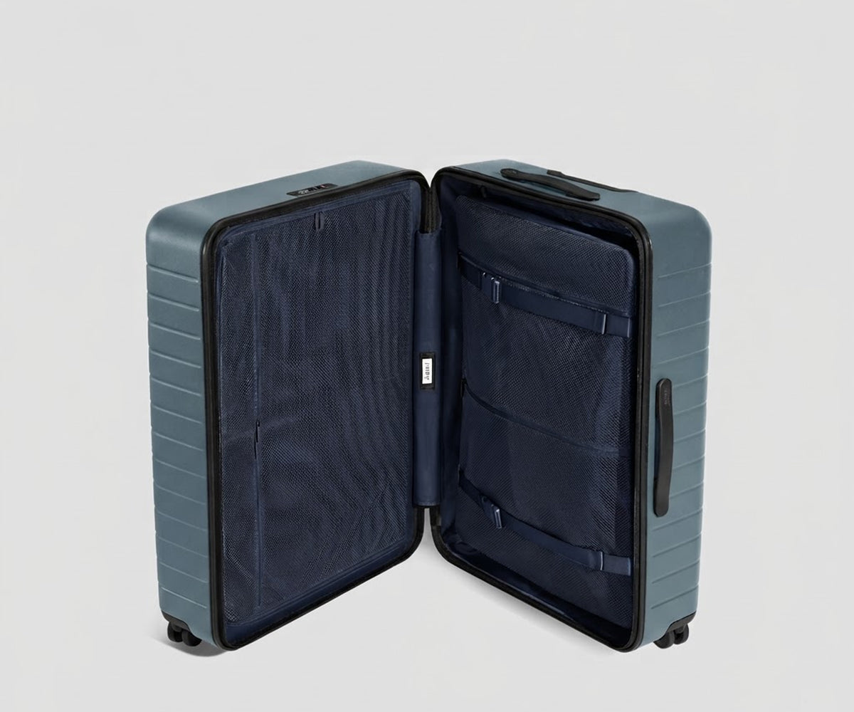 The Large suitcase in Coast Blue shown open in an upright position to show interior organization and compression system