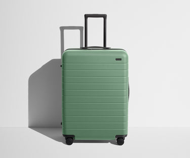 Front product view of The Medium suitcase in Sea Green with raised handle