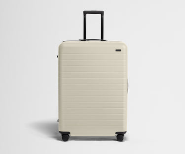 White suitcase with black handle on a light gray background