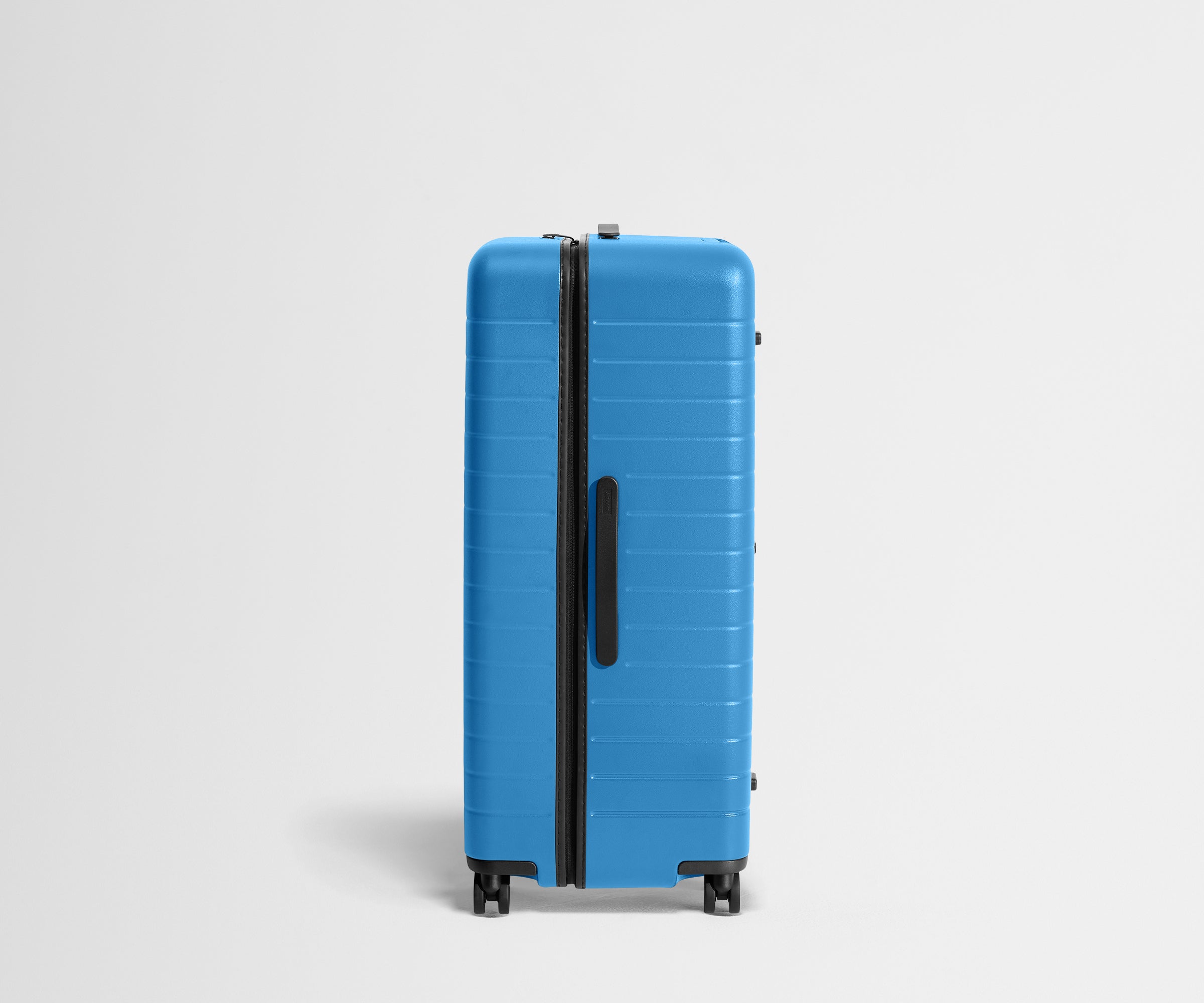 Side product view of The Trunk suitcase in Splash Blue to show the slimmer top lid and deeper main compartment for easy access and packing