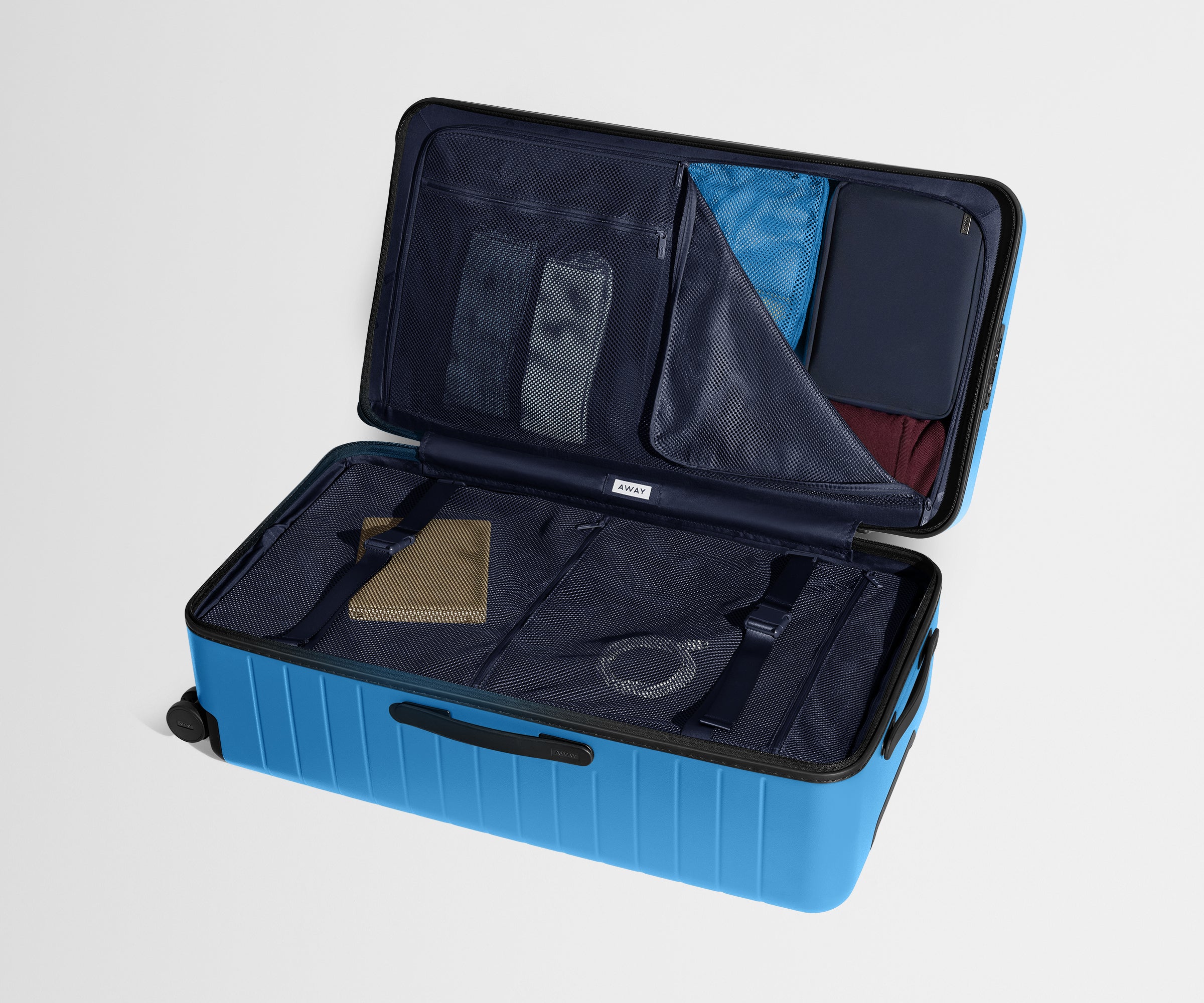 The Trunk suitcase in Splash Blue shown open on its side and packed with Away's packing organizers to show capacity and the interior compression system, designed to help you pack more in