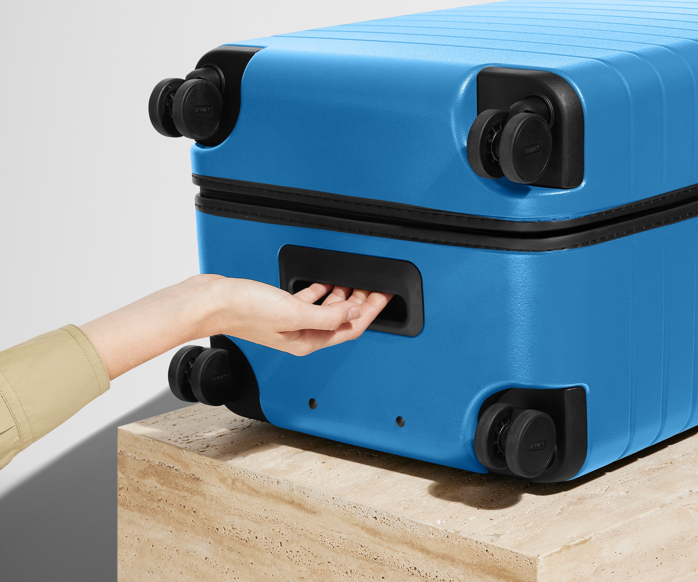 The Trunk suitcase in Splash Blue shown from below highlighting the underside grab handle