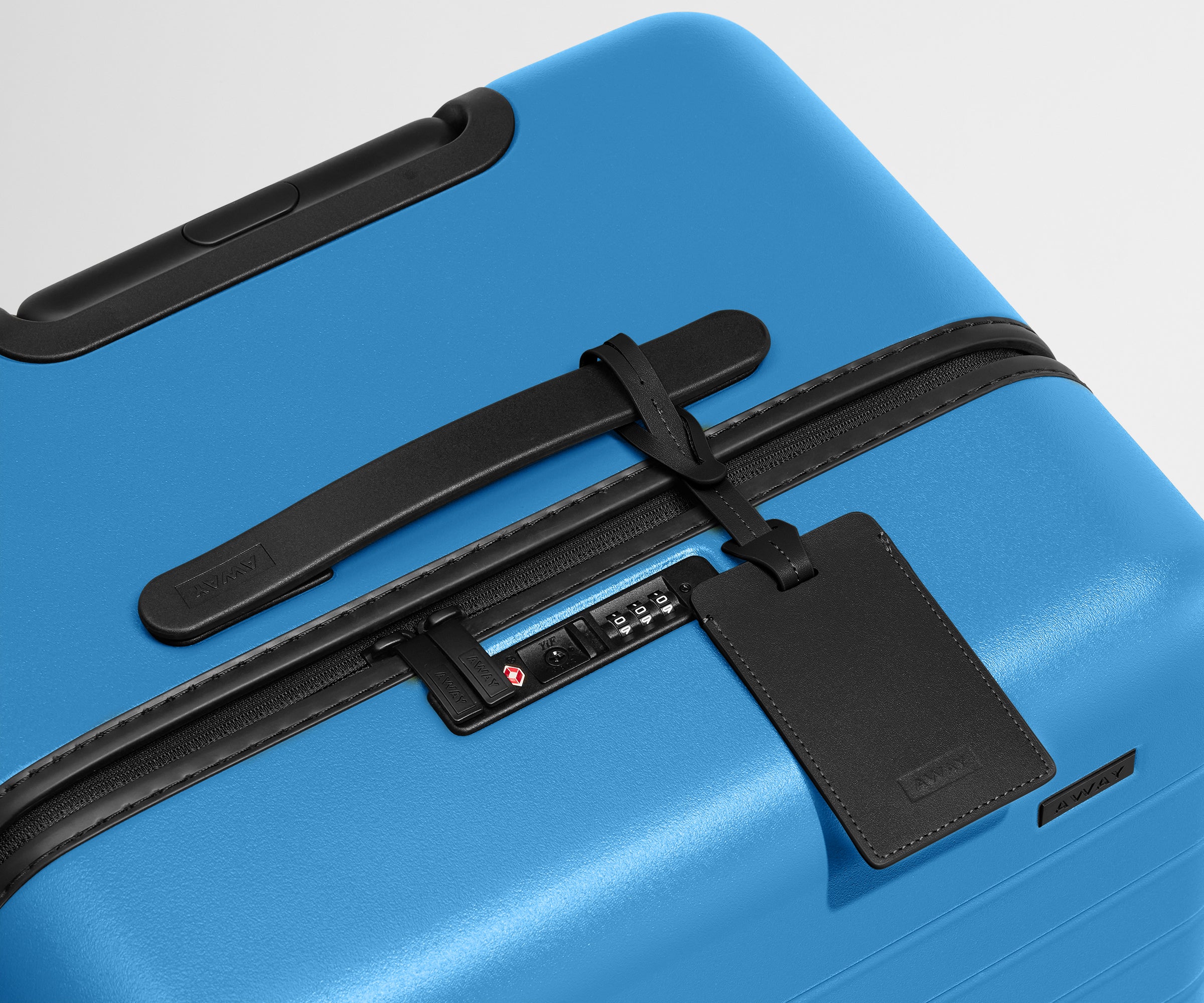 The Trunk suitcase in Splash Blue shown shown from above highlighting TSA-approved combination lock and recycled leather luggage tag