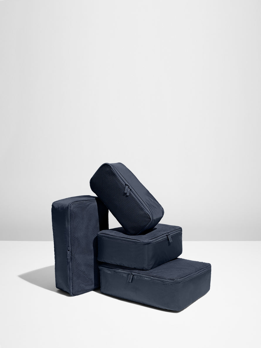 Four Navy Blue packing cubes stacked on each other
