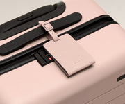 The leather luggage tag on top of a matching Away suitcase
