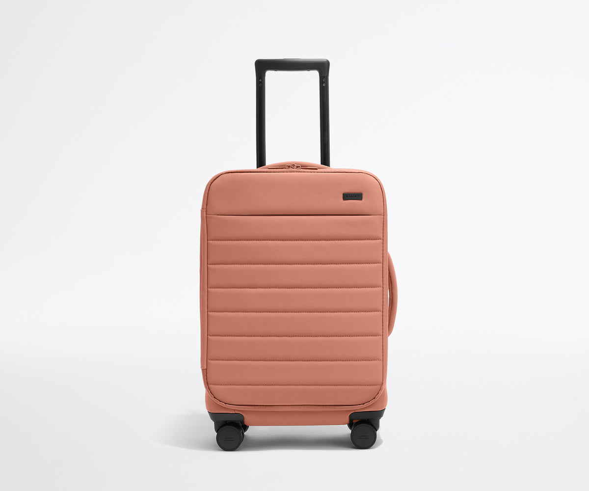 Front product view of The Softside Carry-On suitcase in Clay Pink with raised handle