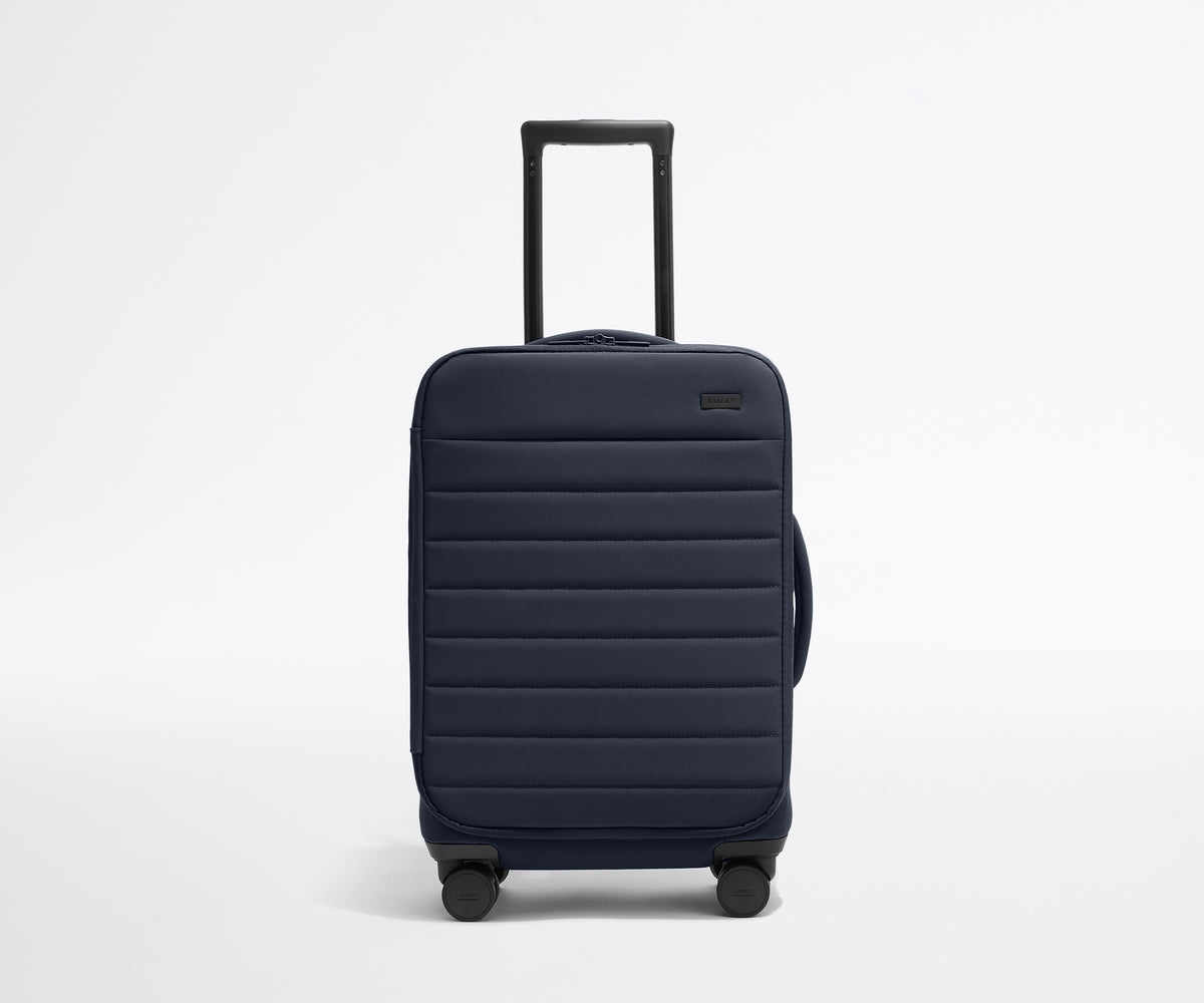 Front product view of The Softside Carry-On suitcase in Navy Blue with raised handle
