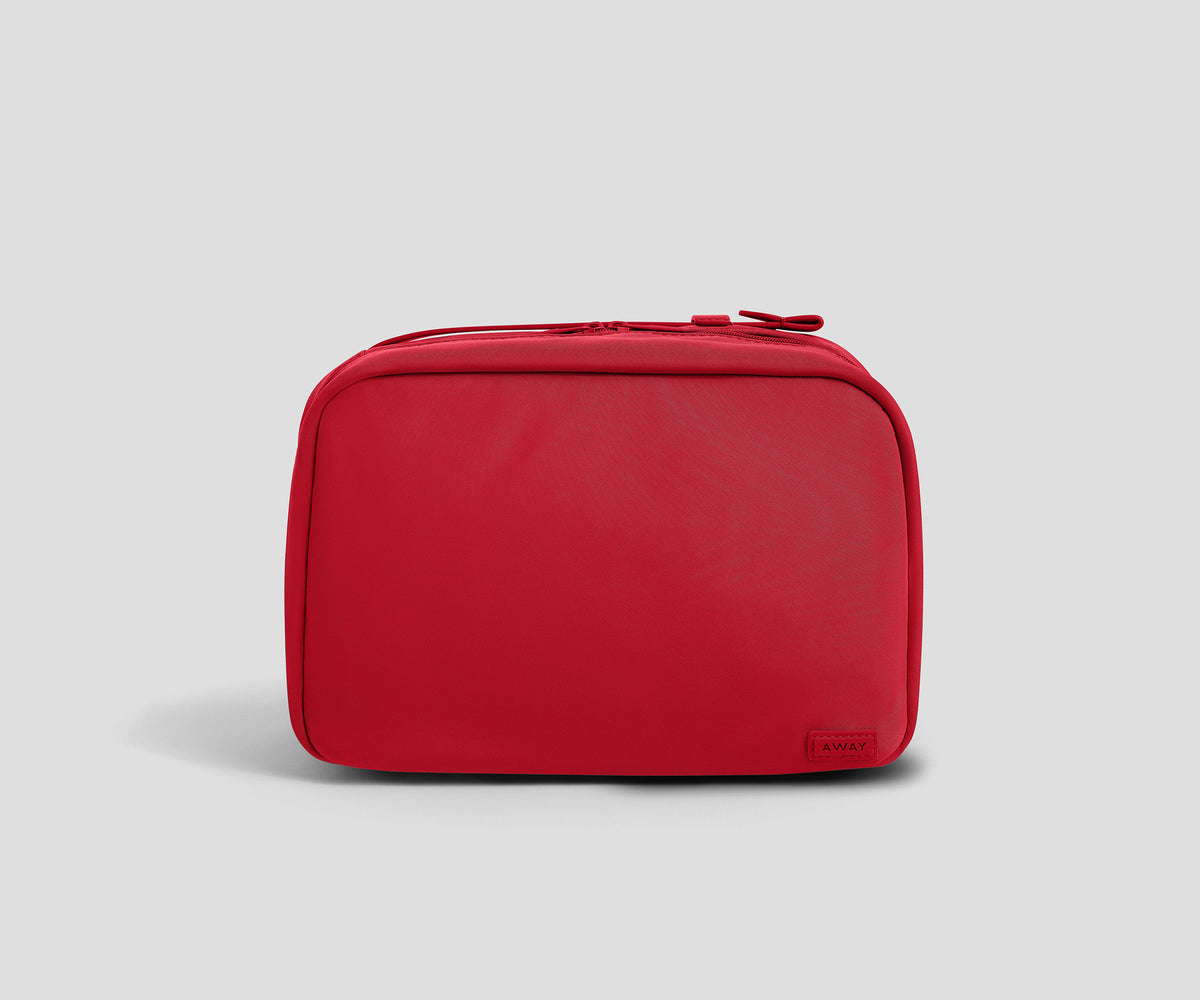 A red zippered toiletry bag with rounded corners, shown from the front on a light gray background.