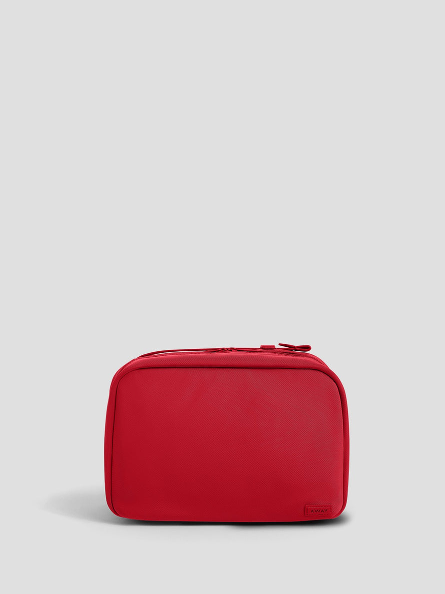A red zippered toiletry bag with rounded corners, shown from the front against a light gray background.