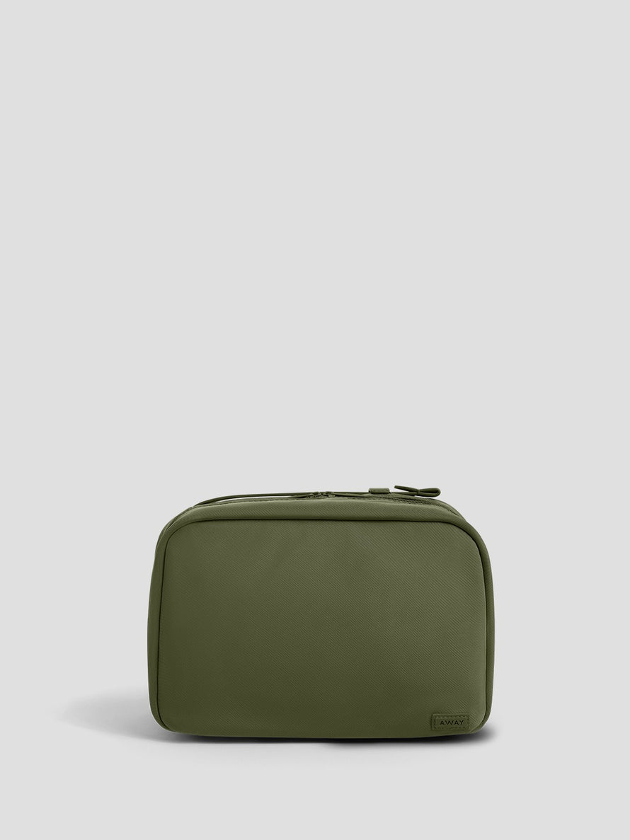 An olive green zippered toiletry bag with a small rectangular brand tab on the bottom right corner, set against a solid light gray background.